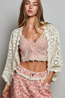 Woman wearing a floral outfit with a white lace cardigan.