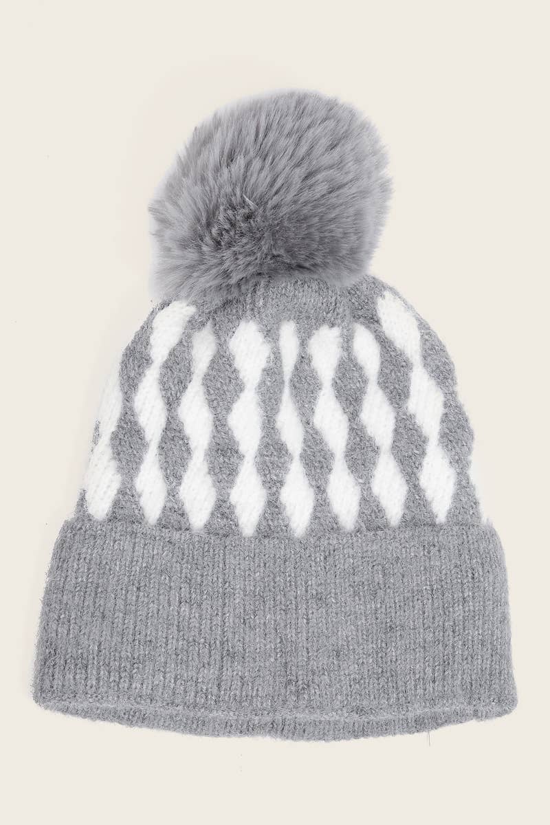 Gray knit beanie with white pattern and gray pom-pom on a beige background