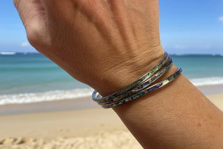 Abalone Bangle laid flat, showing its coastal-inspired charm and clasp