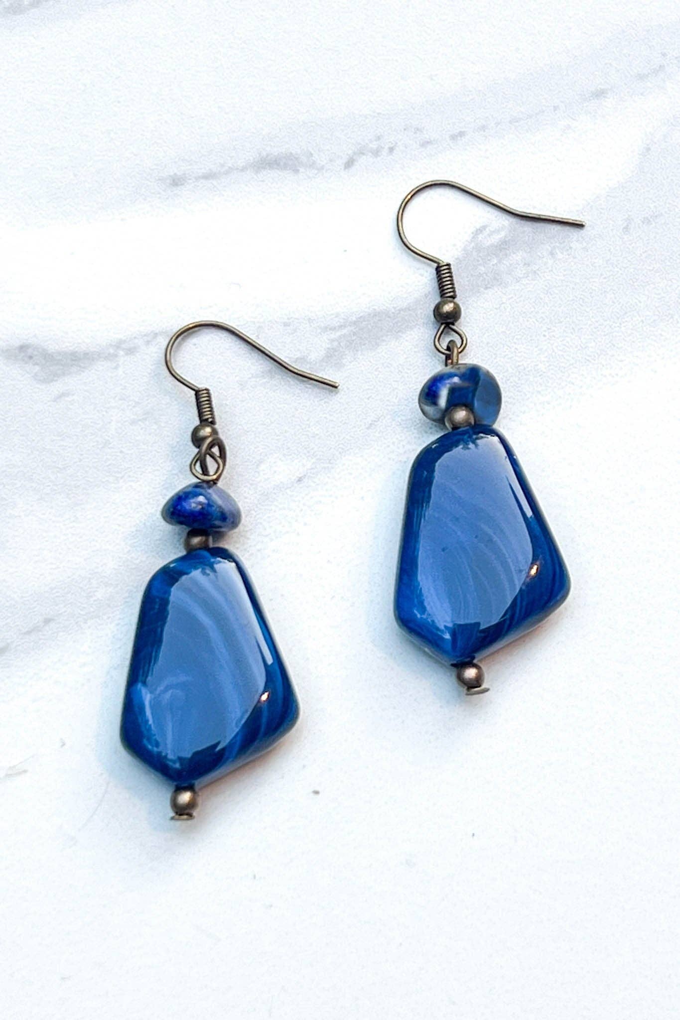 Blue teardrop-shaped earrings on a white marble background