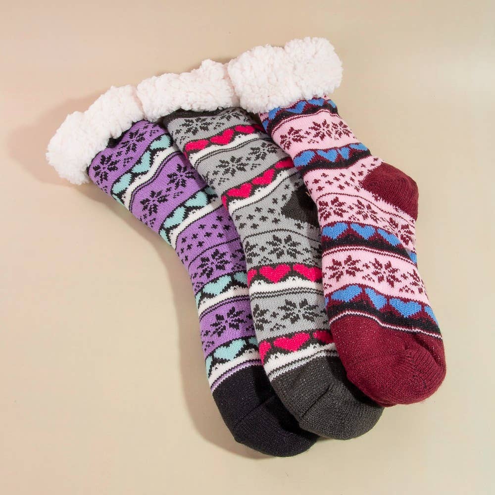 Three pairs of patterned socks with white fuzzy tops on a beige background