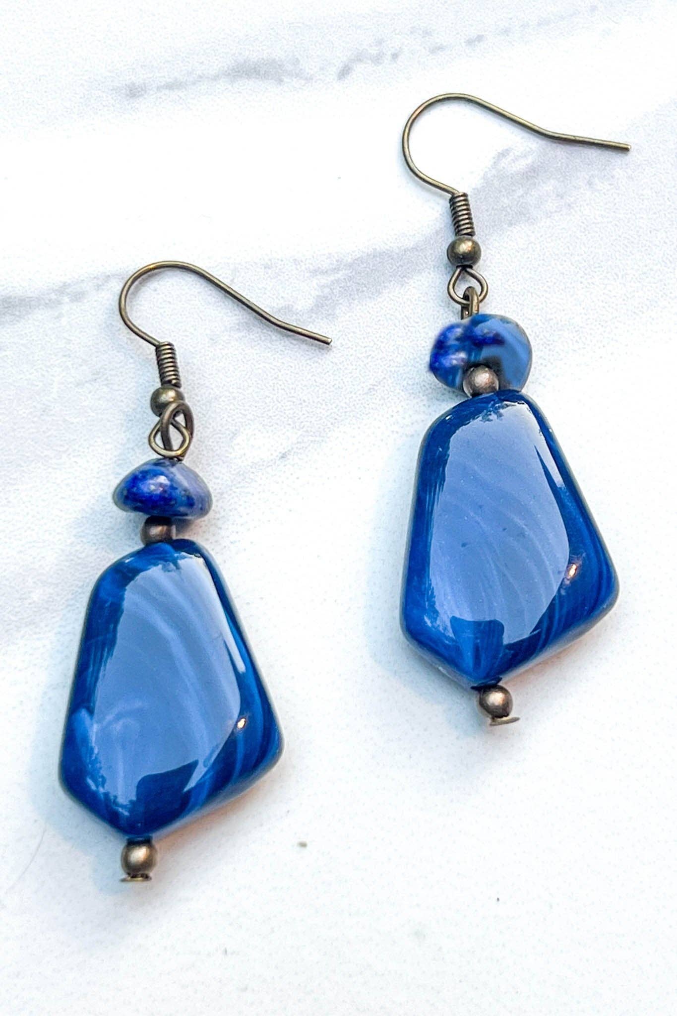 Blue beaded earrings on a white marble surface