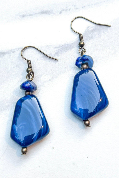 Blue beaded earrings on a white marble surface