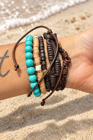 A close-up of a person's wrist wearing a stack of bohemian-style bracelets, including turquoise beads, wooden beads, and dark brown cords