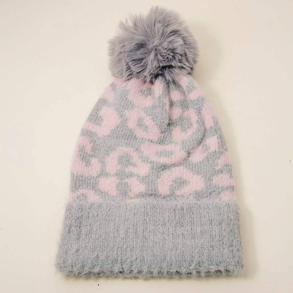 Gray and pink patterned knit hat with a pom-pom on a light beige background