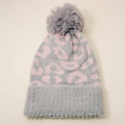 Gray and pink patterned knit hat with a pom-pom on a light beige background
