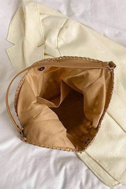 Brown woven bag on a white surface with beige fabric