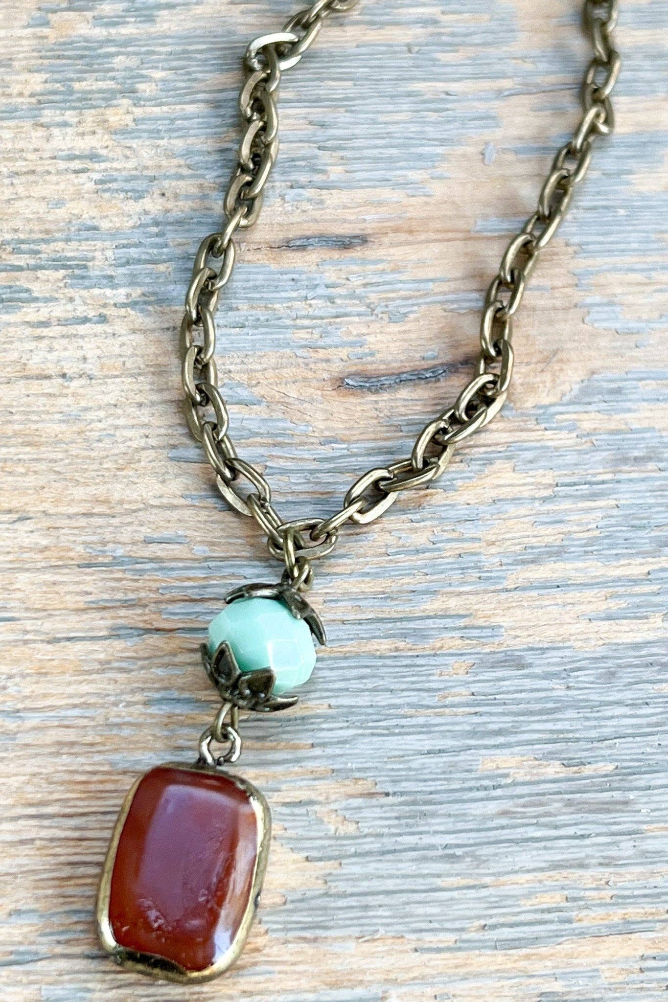 Necklace with chain and two pendant stones on a wooden surface