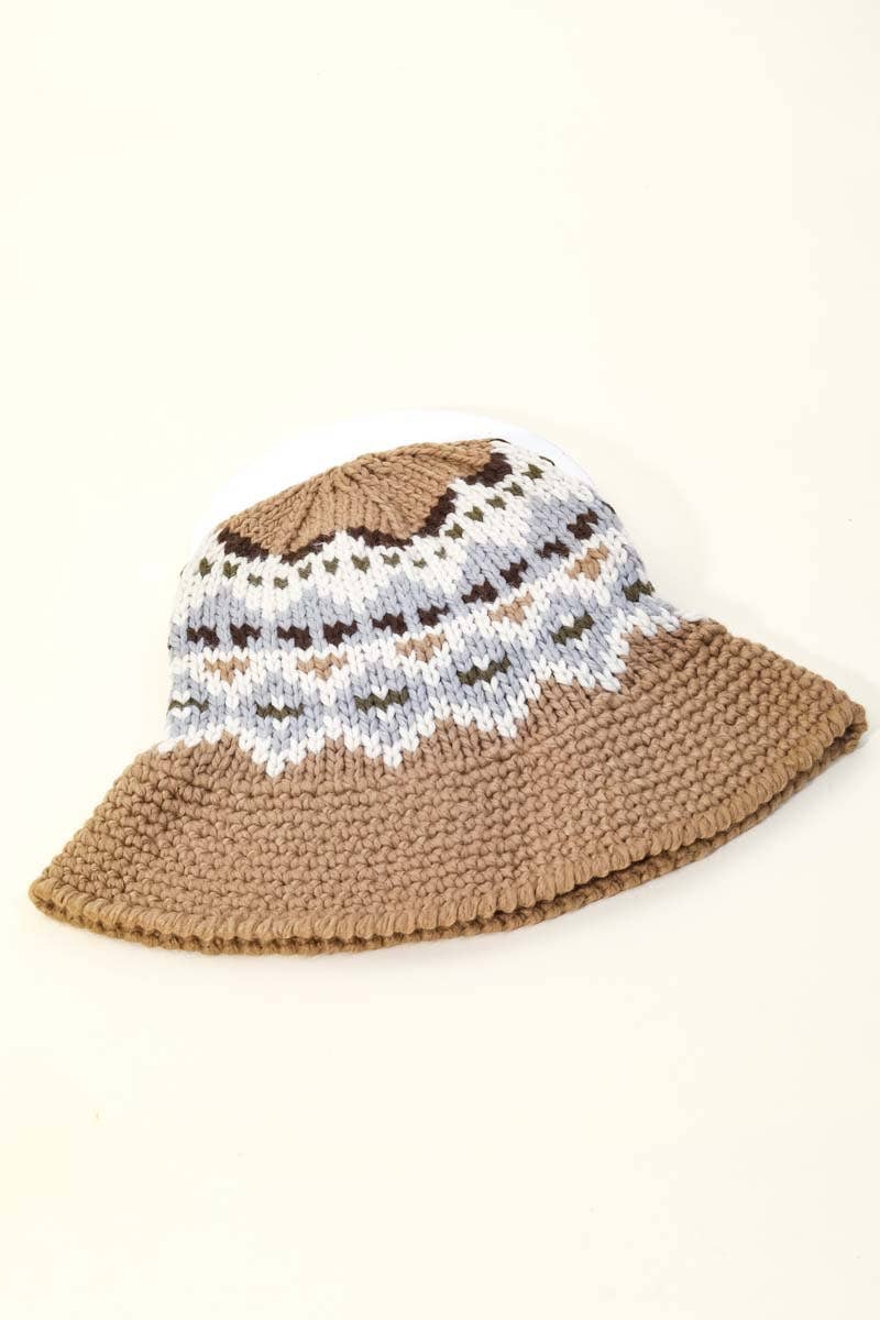 Brown crochet hat with a white and brown patterned brim on a beige background