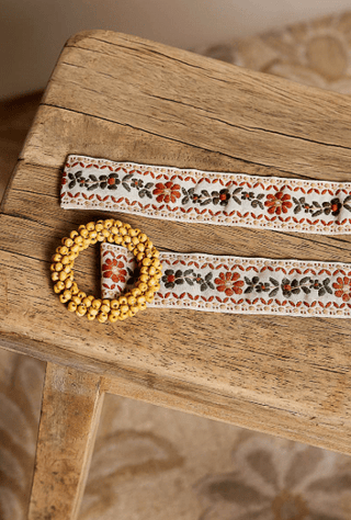 Cream Floral Belt with Bead Buckle laid flat to show its buckle and woven texture