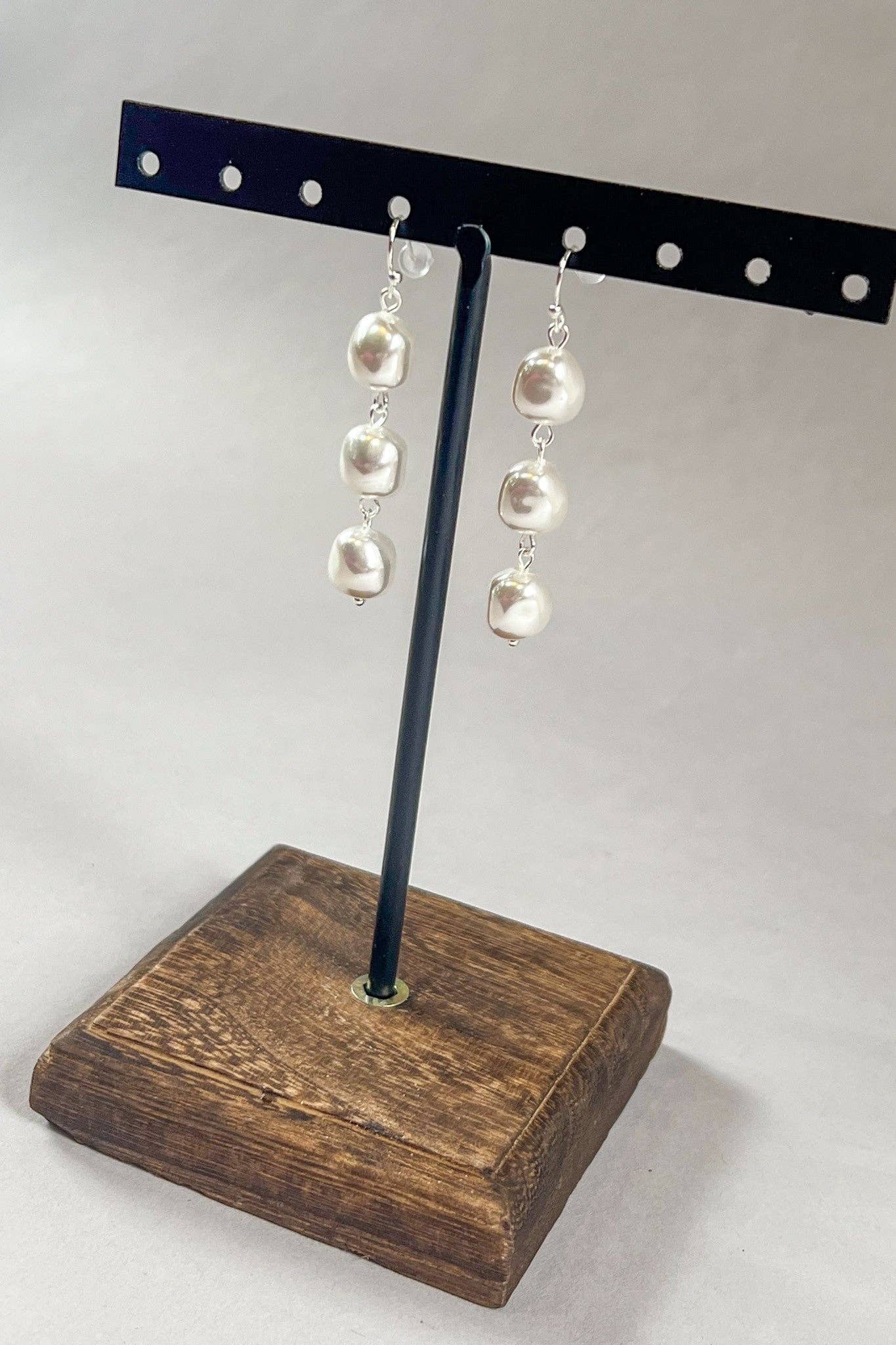 Pearl earrings on a wooden stand with a white background