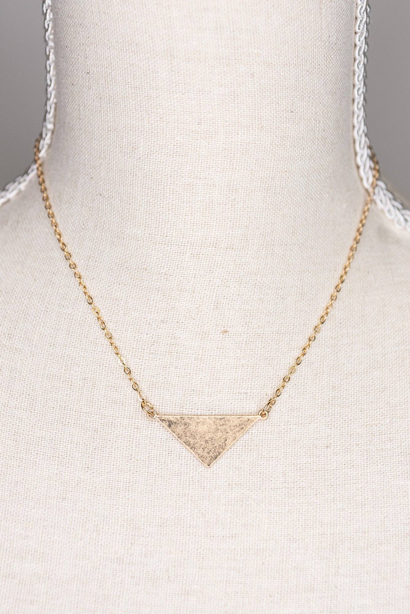 Gold triangle pendant necklace on a mannequin bust.