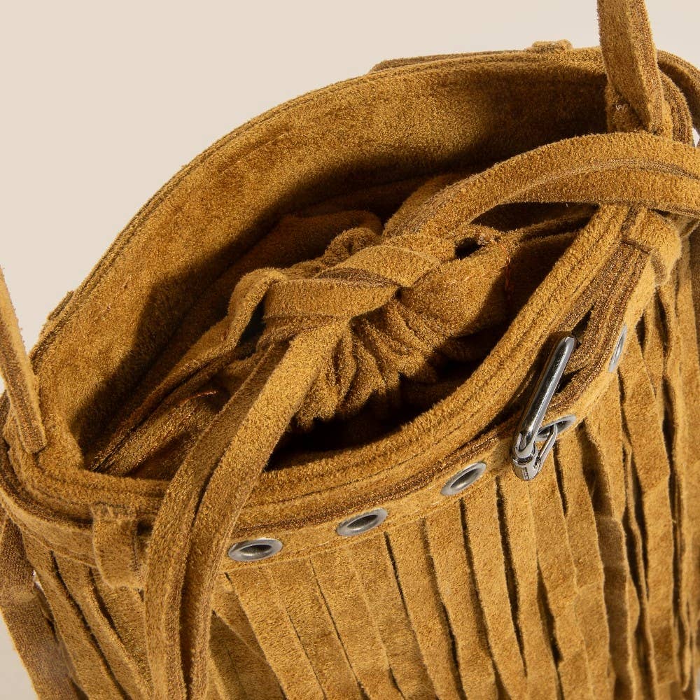 Close-up of a brown suede handbag with fringes and braided details.