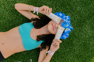 Person lying on grass with blue flower crown and colorful bracelets