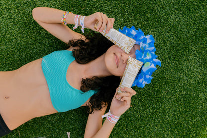 Person lying on grass with blue flower crown and colorful bracelets