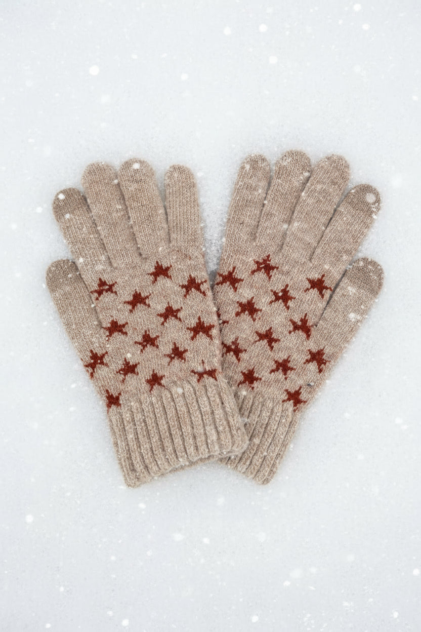 Pair of beige gloves with red star patterns on a white snowy background
