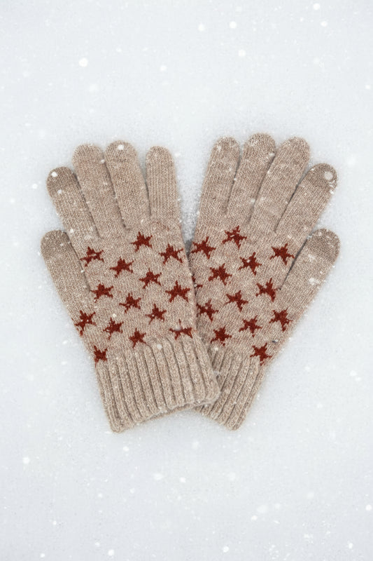 Pair of beige gloves with red star patterns on a white snowy background