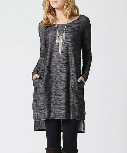 Woman wearing a long dark gray tunic with pockets on a white background