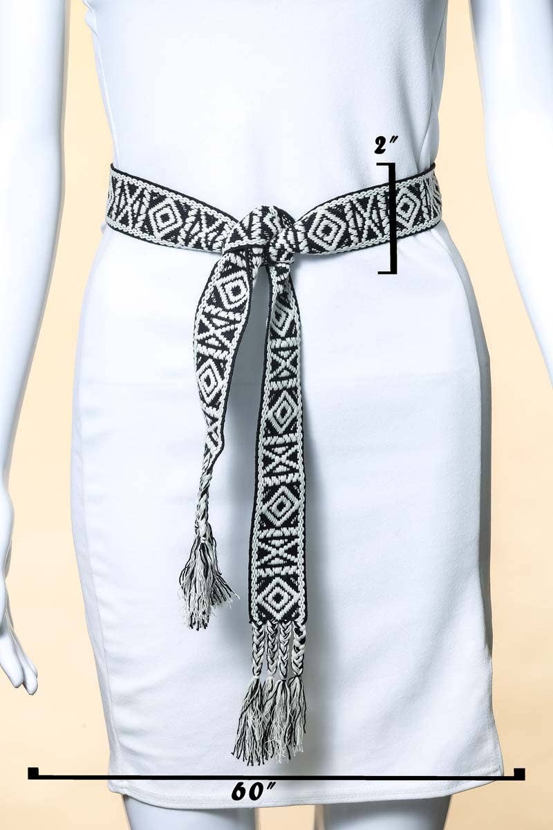 White dress with a black and white patterned belt on a beige background