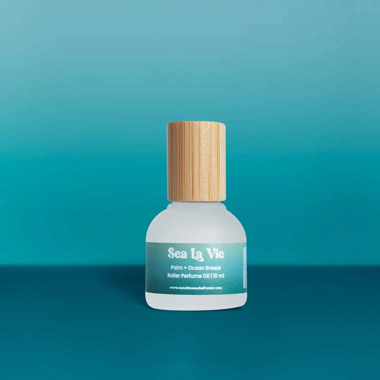 Sea La Vie perfume bottle with wooden cap on a teal background