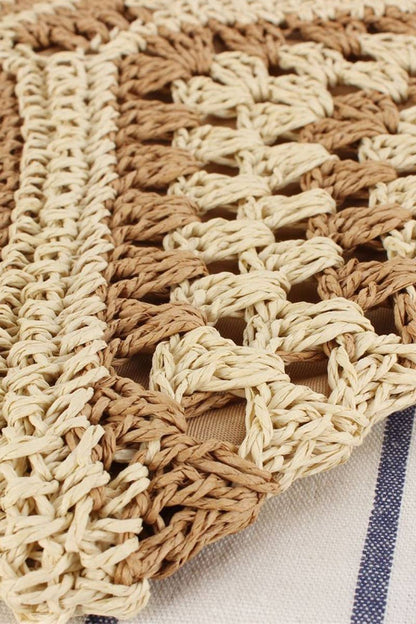 Close-up of a woven bag with beige and brown pattern on a neutral background