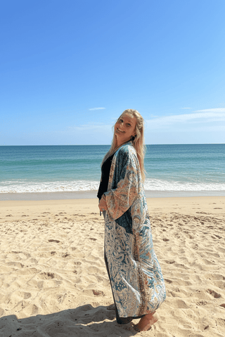 Woman wearing a patched, patterned kimono robe standing on the beach