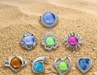 Set of colorful mood stone rings on a sandy background