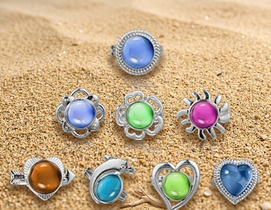 Set of colorful mood stone rings on a sandy background