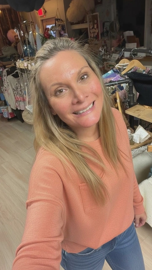 video showing woman wearing coral colored soft looking sweater