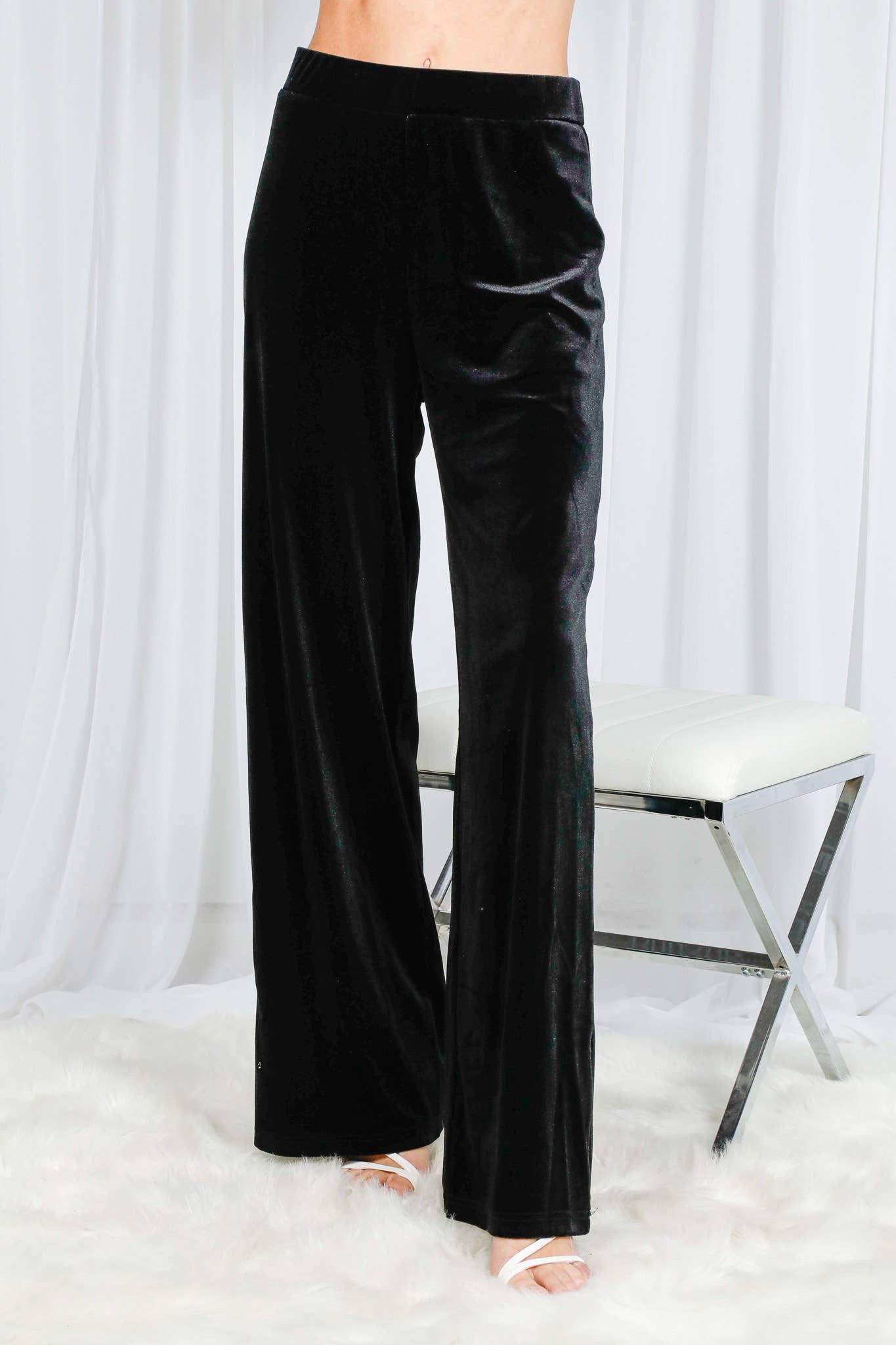 Black velvet pants worn by a person on a white background